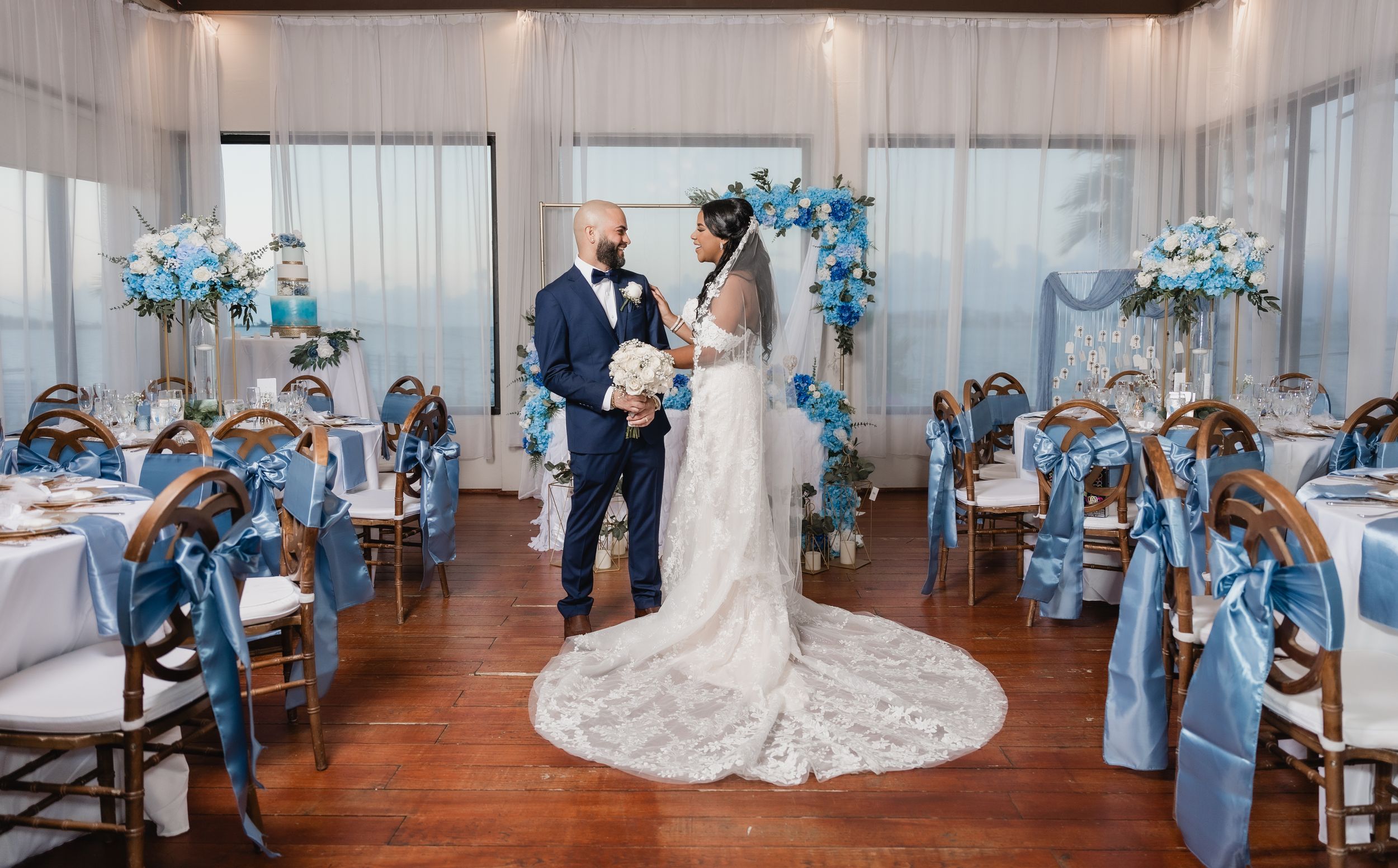 Wedding ceremony setup with light blue floral arrangements and elegant white drapery.