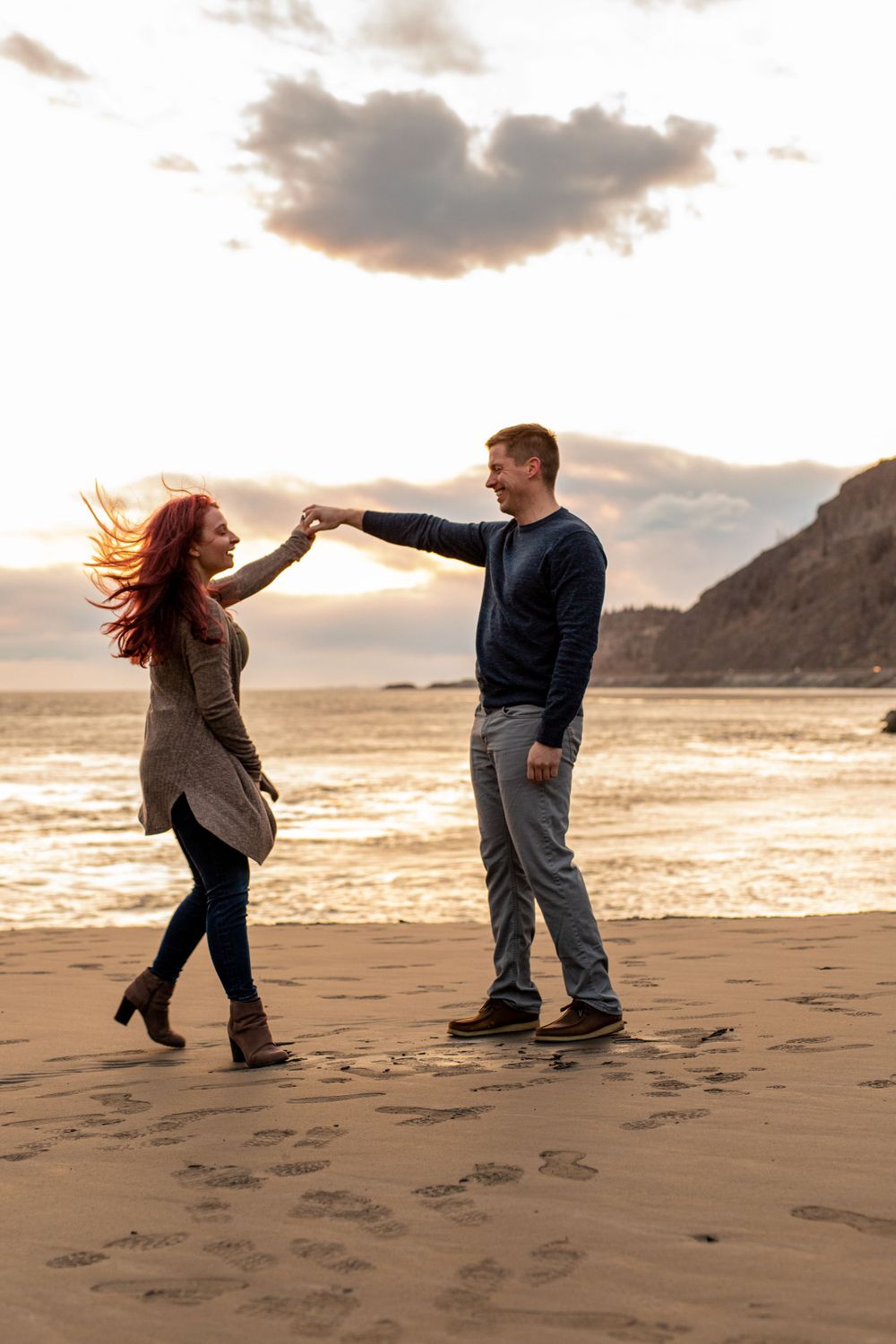 A romantic dance on the beach at sunset with mountains in the background.