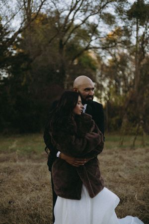 A couple snuggles for warmth during their November wedding portraits in Michigan.