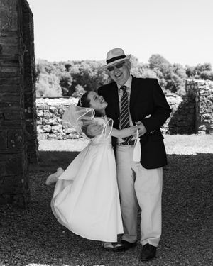 Black and white photos of wedding couple dancing and celebrating under stone archway.
