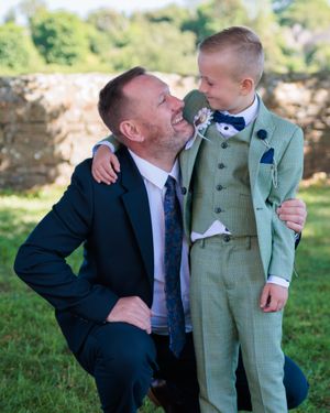 A touching moment between two people wearing suits outdoors.