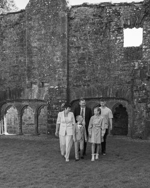 Three people stand in front of stone archways in a vintage black and white photograph.