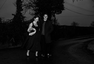 Vintage black and white photo of a couple standing on a dark country road at night.