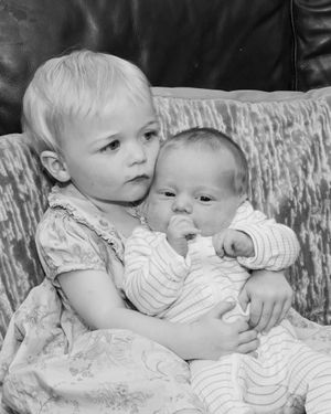 Black and white series of two young children sharing tender moments on a textured couch.