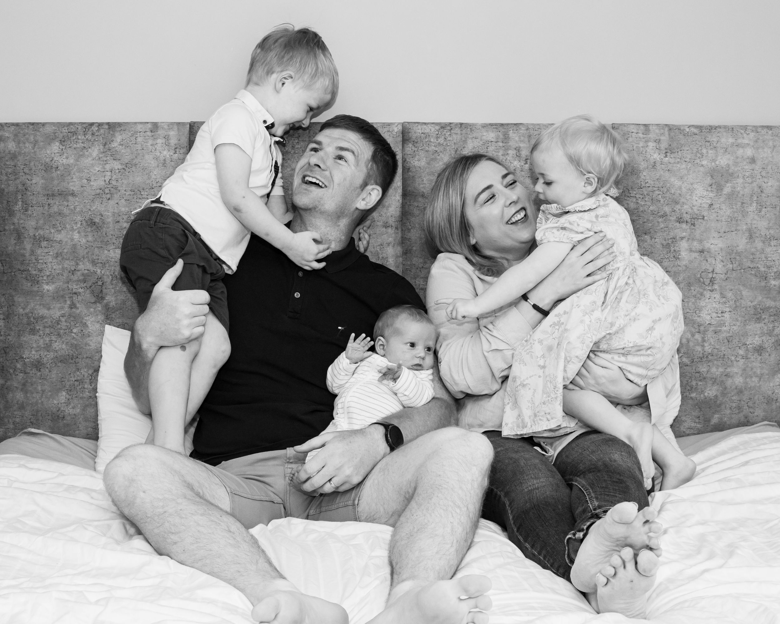 Black and white photo series of relaxed family moments on a comfortable bed.