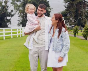 Family photo series on a green lawn with white picket fence showing joyful moments together.