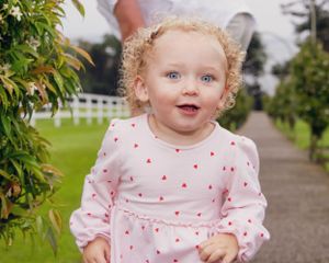 Sweet toddler in pink polka dot dress exploring outdoors with curious expressions.