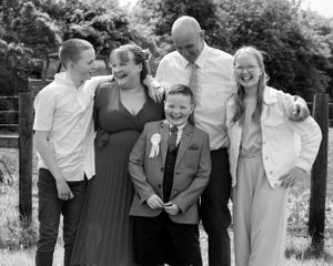 A family of five posing together outdoors for a formal black and white portrait.