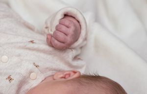 Detailed close-up shots of a baby wearing white lace clothing against white fabric.
