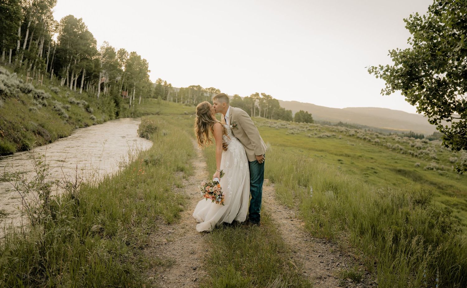 A newly married couple dancing in a hay field with the sunset in the background