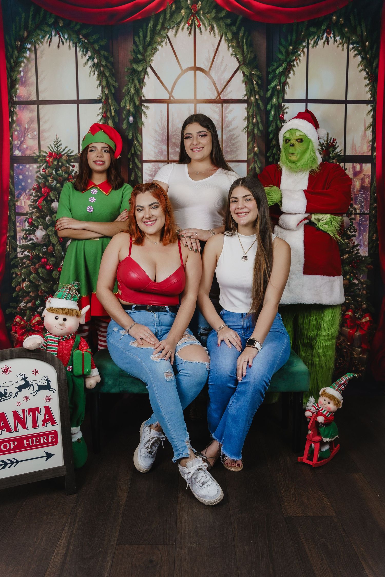 Group holiday photo with Grinch characters and festive decorations in Christmas setting.