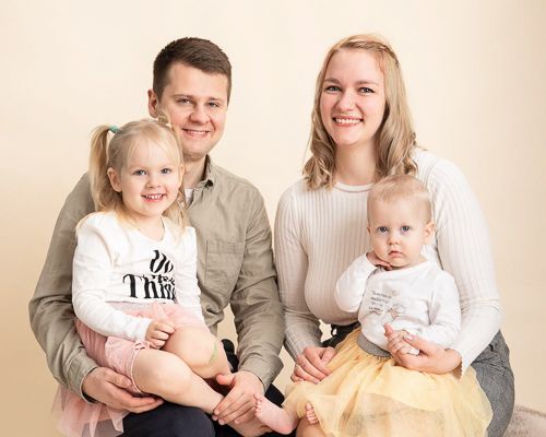Family photo session showing coordinated outfits in neutral tones against light background.