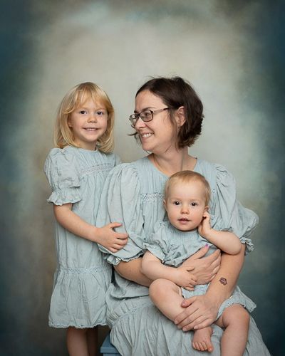 Three dreamy portraits of mother and children in matching light blue dresses against a moody backdrop.