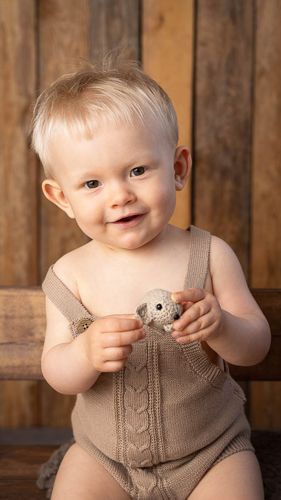 A series of photos showing a baby wearing a tan knit romper against a rustic wooden background.