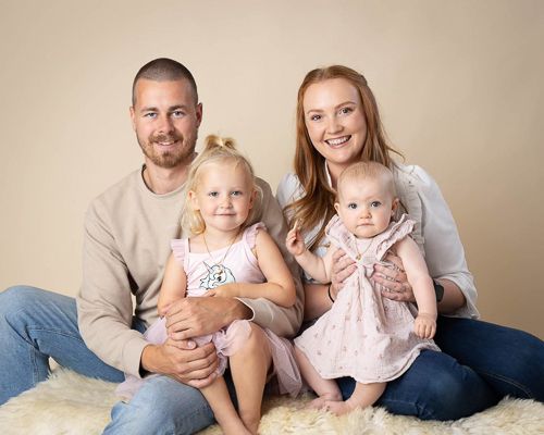 A loving family lies together on a beige couch in a series of casual portrait photos showing warm connections.