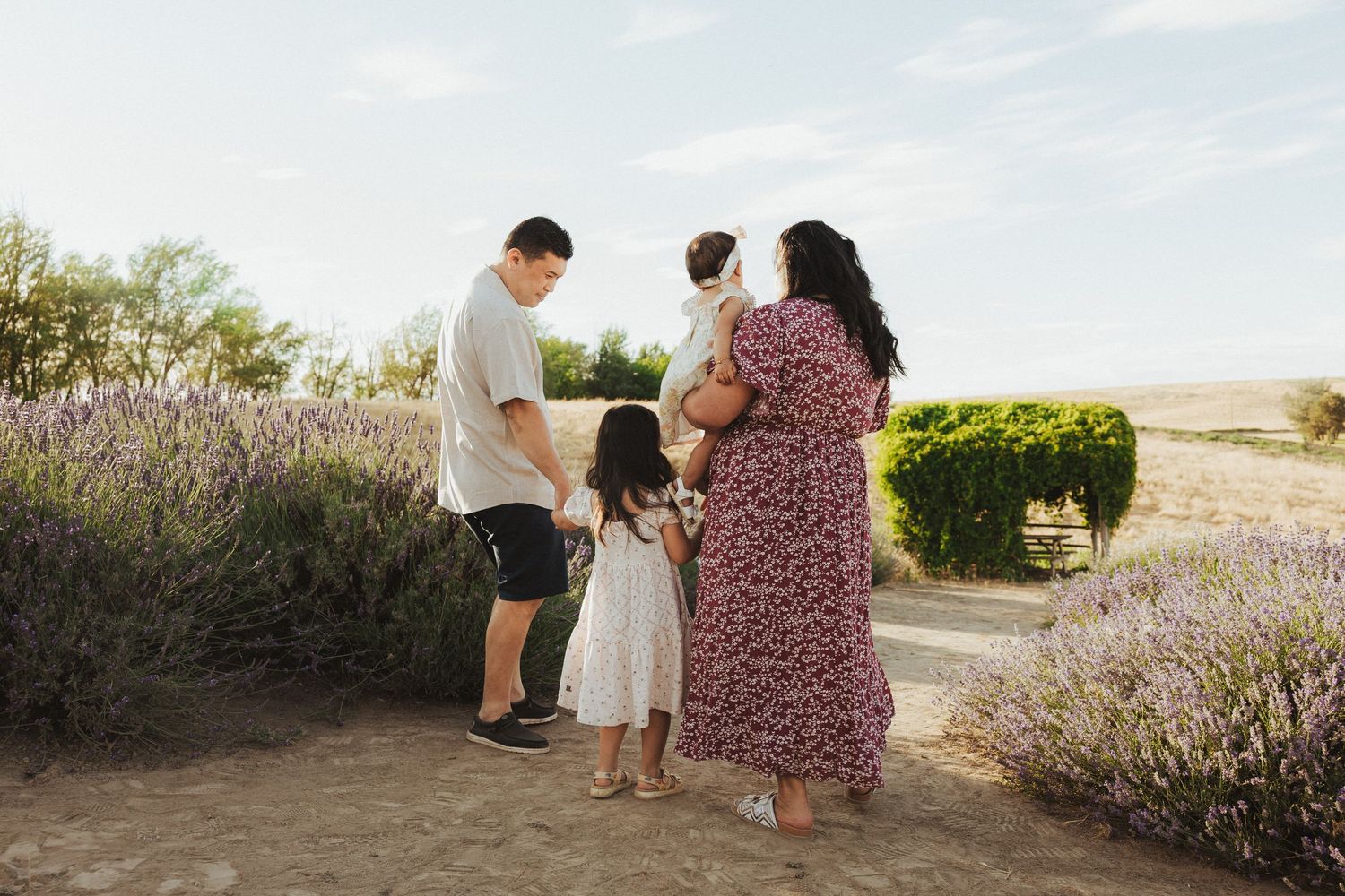 a family of three including one small child sitting in a sunny field smiling at the camera