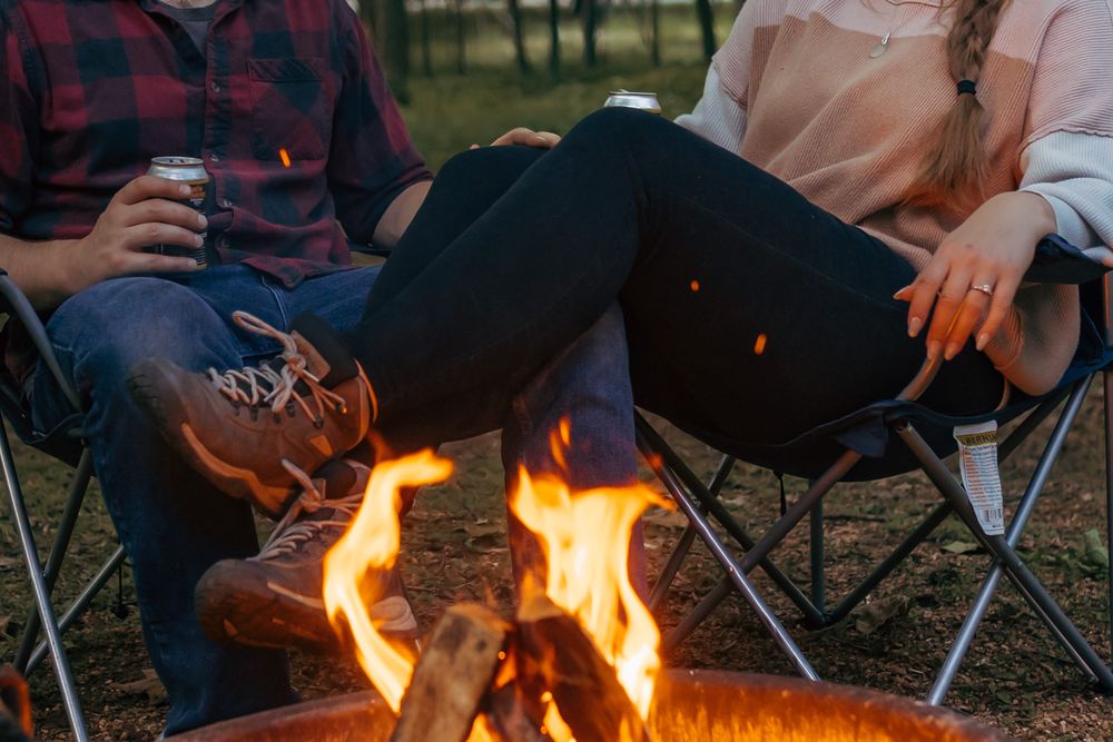 Detail photo of an engaged couple sitting by the fire and drinking beer during their engagement session in Mosinee, Wisconsin