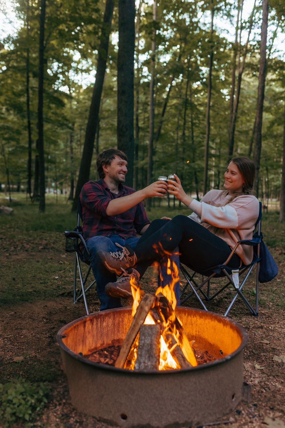 Engaged couple celebrating by the fire during their outdoor engagement session in Mosinee, Wisconsin