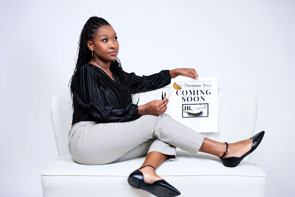 Studio portrait of person in black top and striped skirt posing with promotional materials.