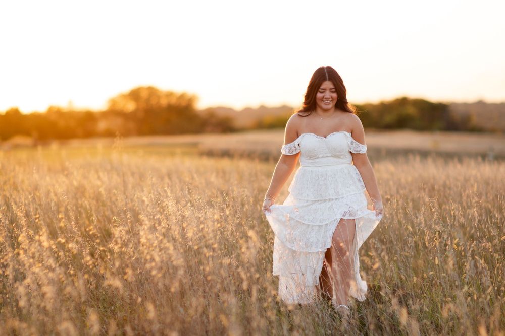 A white lace dress flows gracefully in a golden field during sunset.