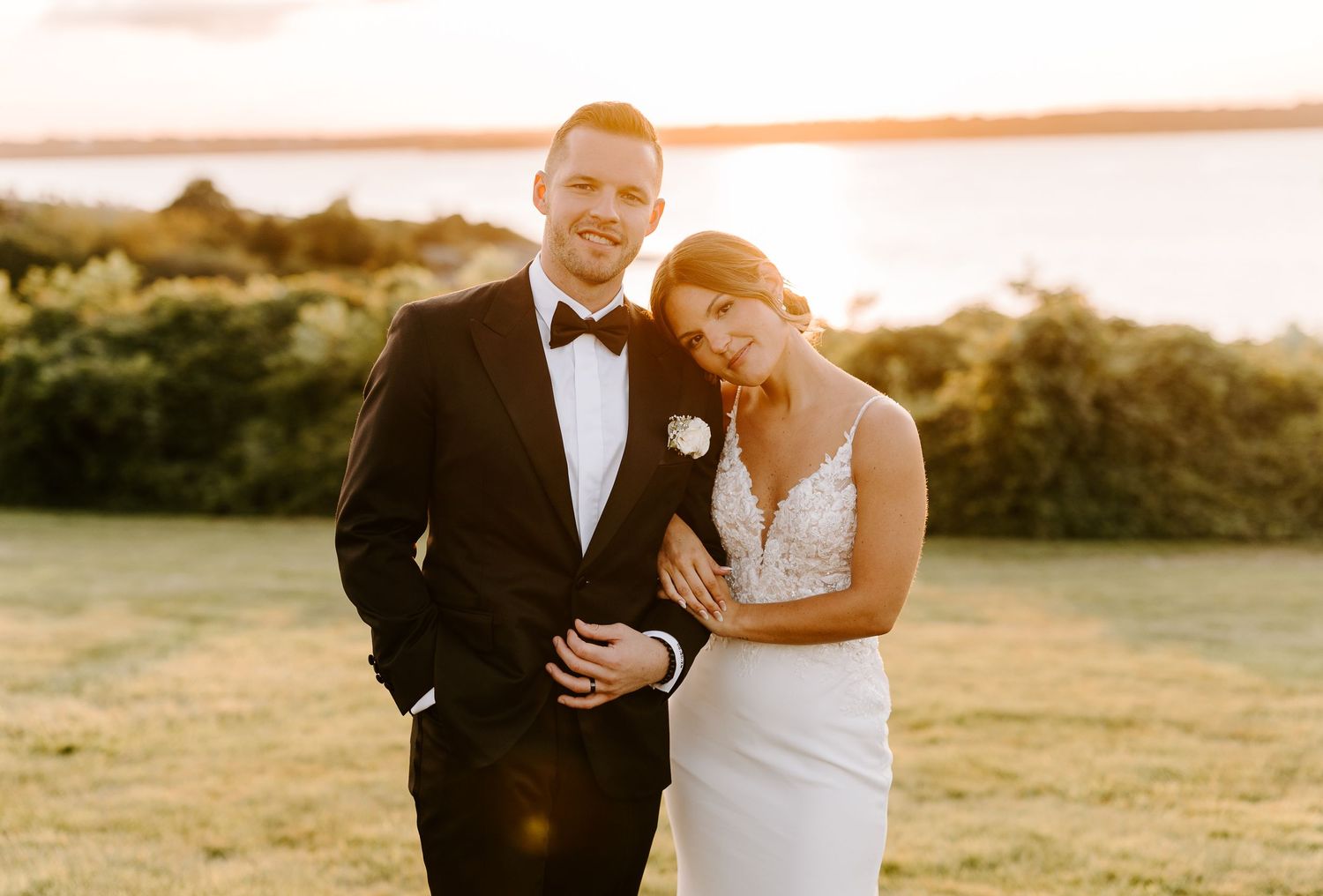 Romantic sunset portrait session with couple in formal attire on grassy hillside.