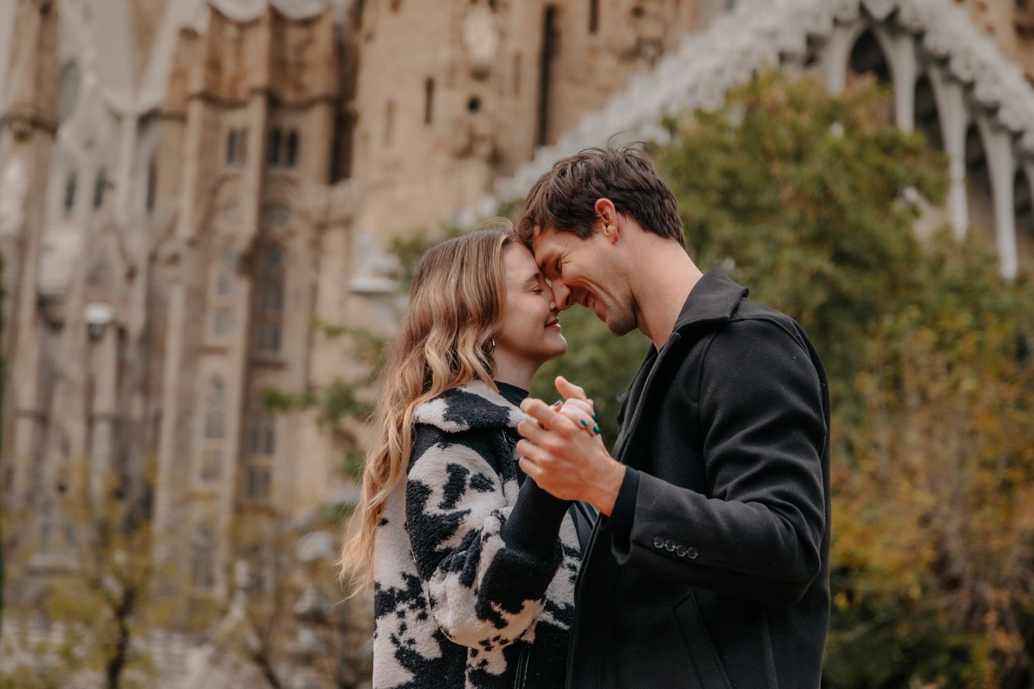 A loving couple posing for their 5th-anniversary photoshoot with the magnificent Sagrada Família