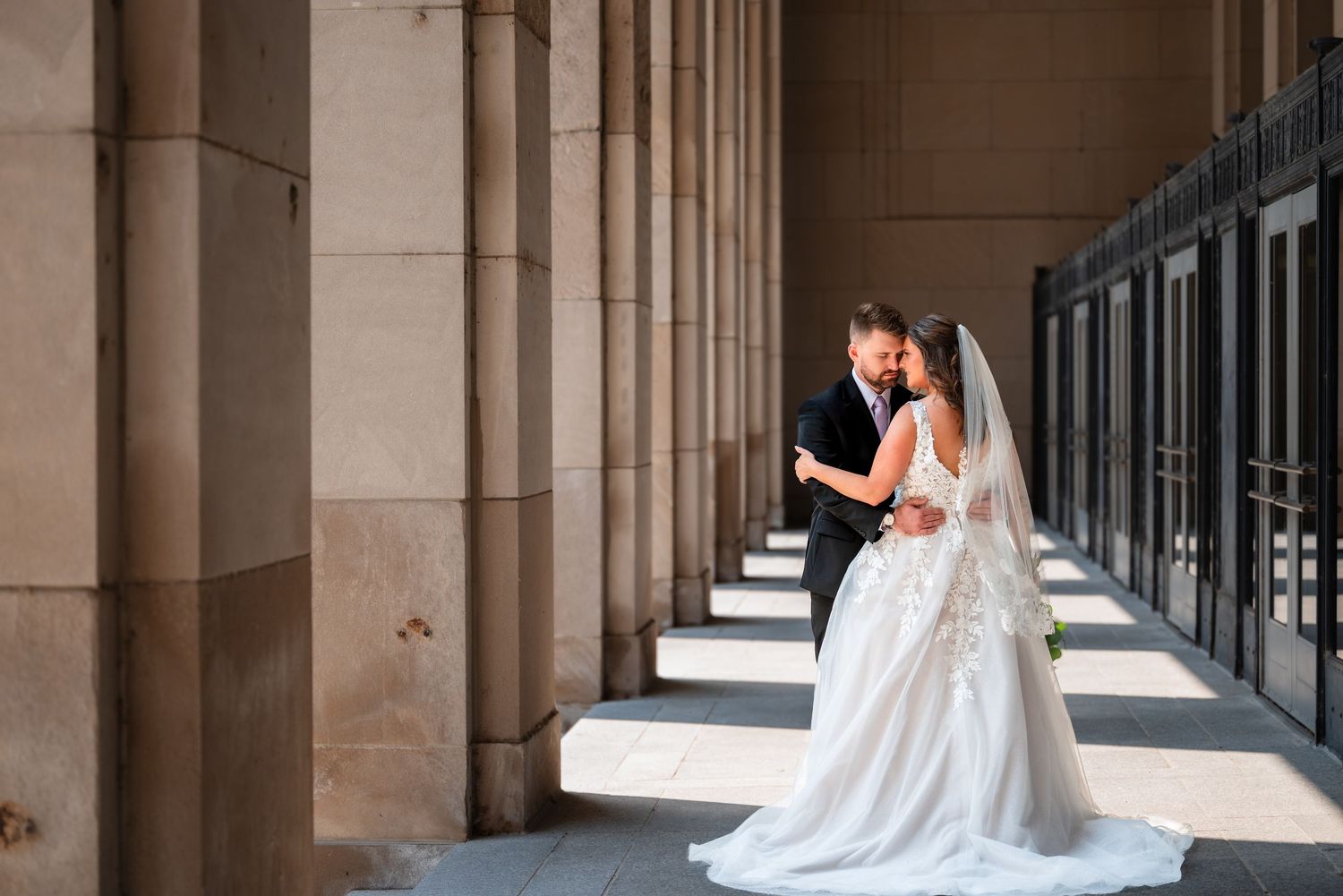 Romantic couple embracing near waterfront with chicago skyline, man in black suit, woman in white dress.