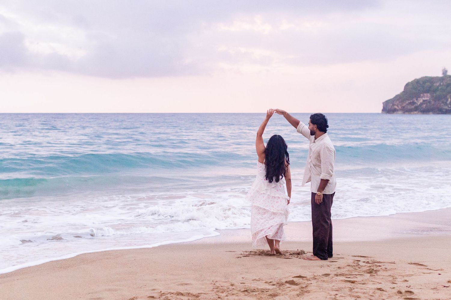 Engagement portrait on the beach. Man twirling woman at the water's edge. Playa Guajataca, Isabela, Puerto Rico.