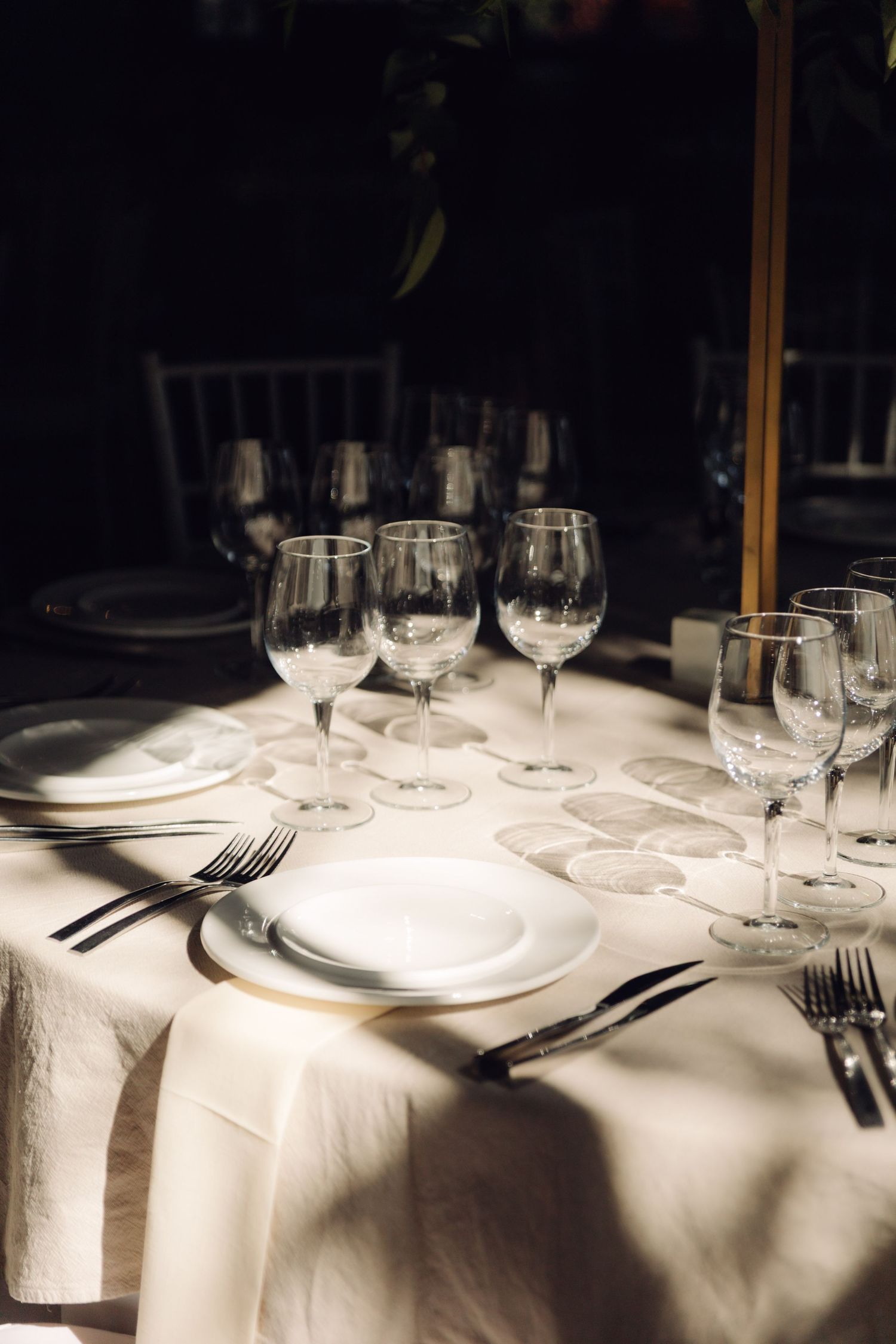 Elegant wedding table setting with white linens, crystal glasses, and fine dinnerware.