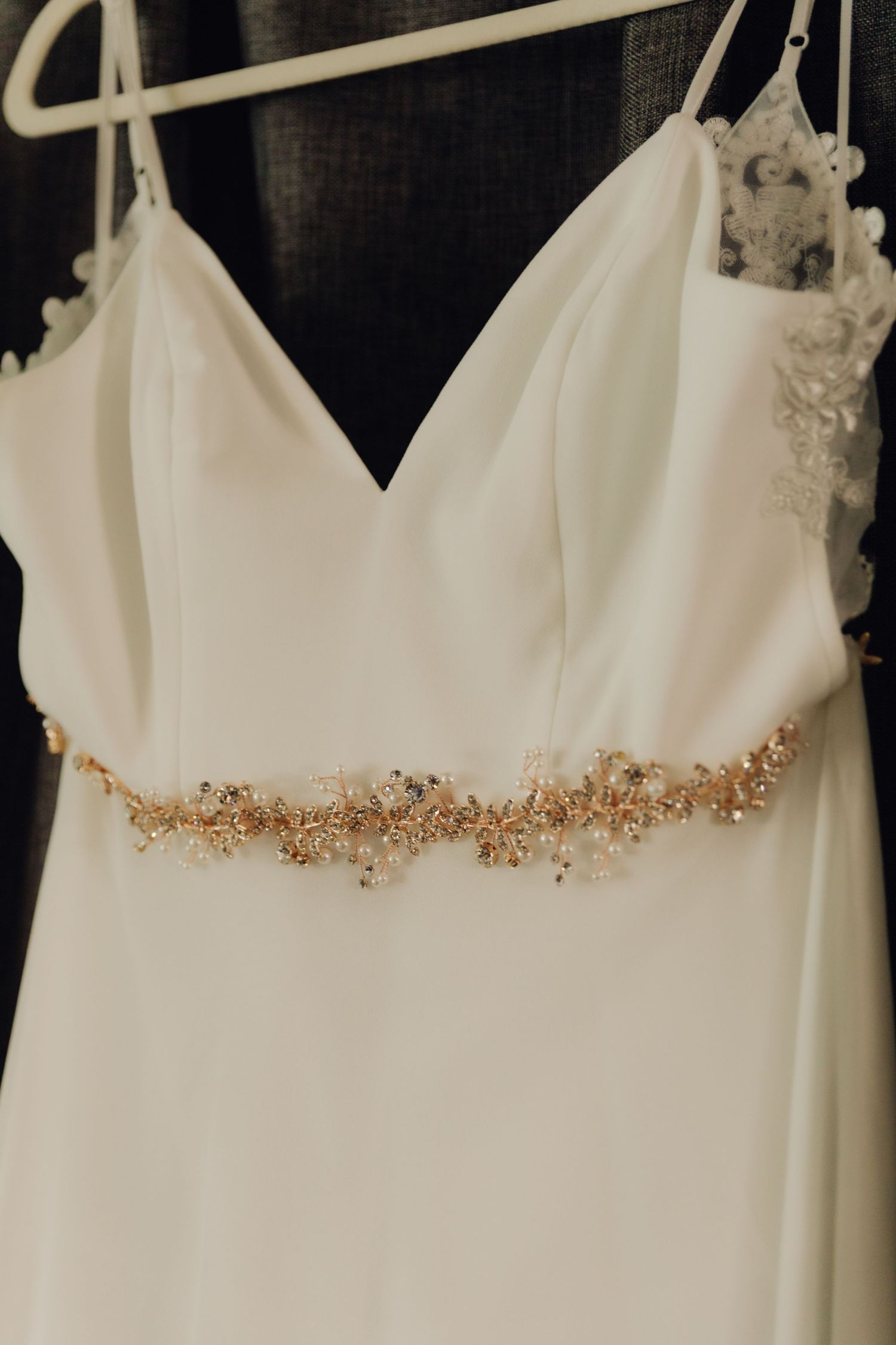 Close-up of a white wedding dress bodice with a delicate gold beaded belt detail.