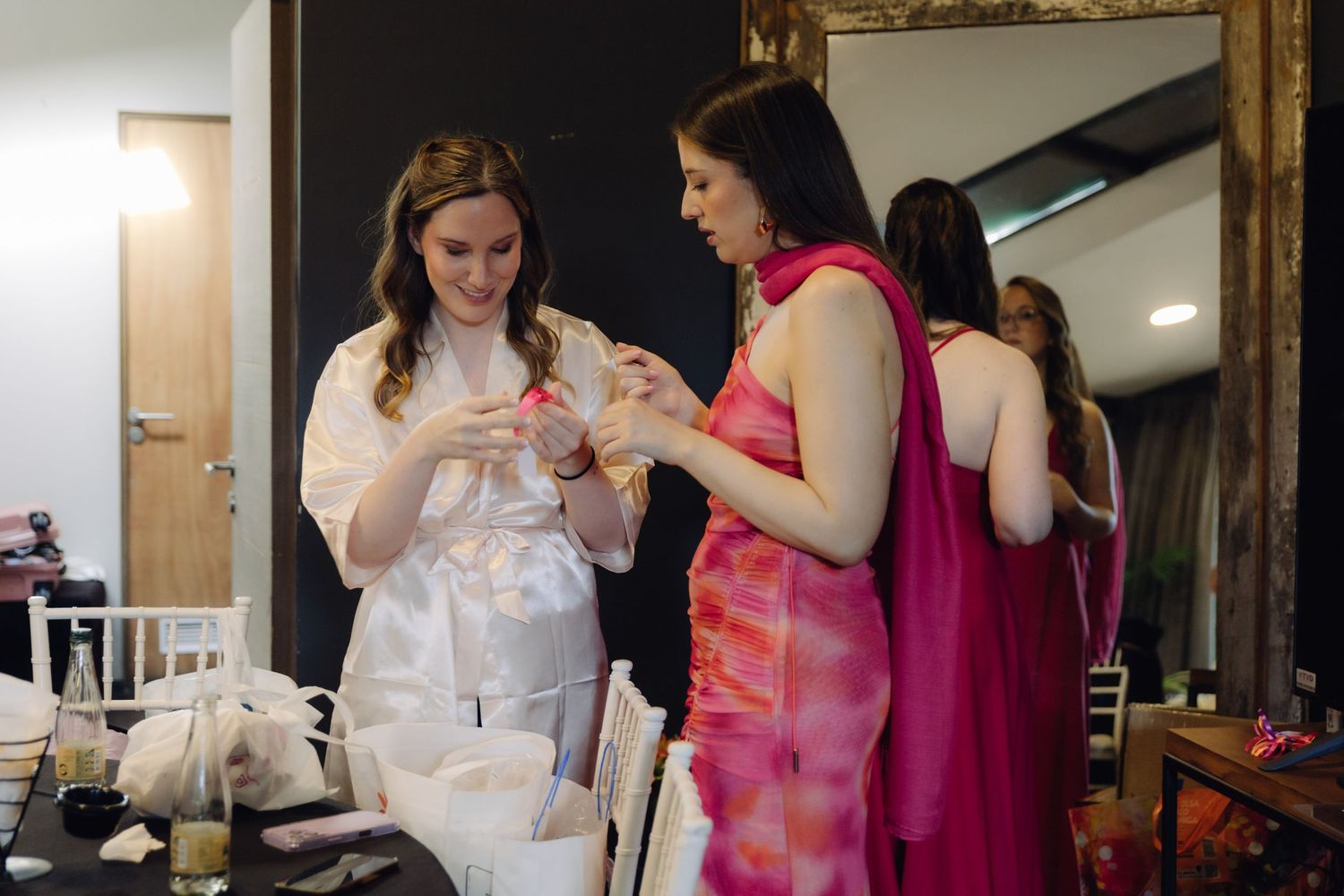 Bride in white robe with bridesmaids in pink dresses preparing before the wedding ceremony.