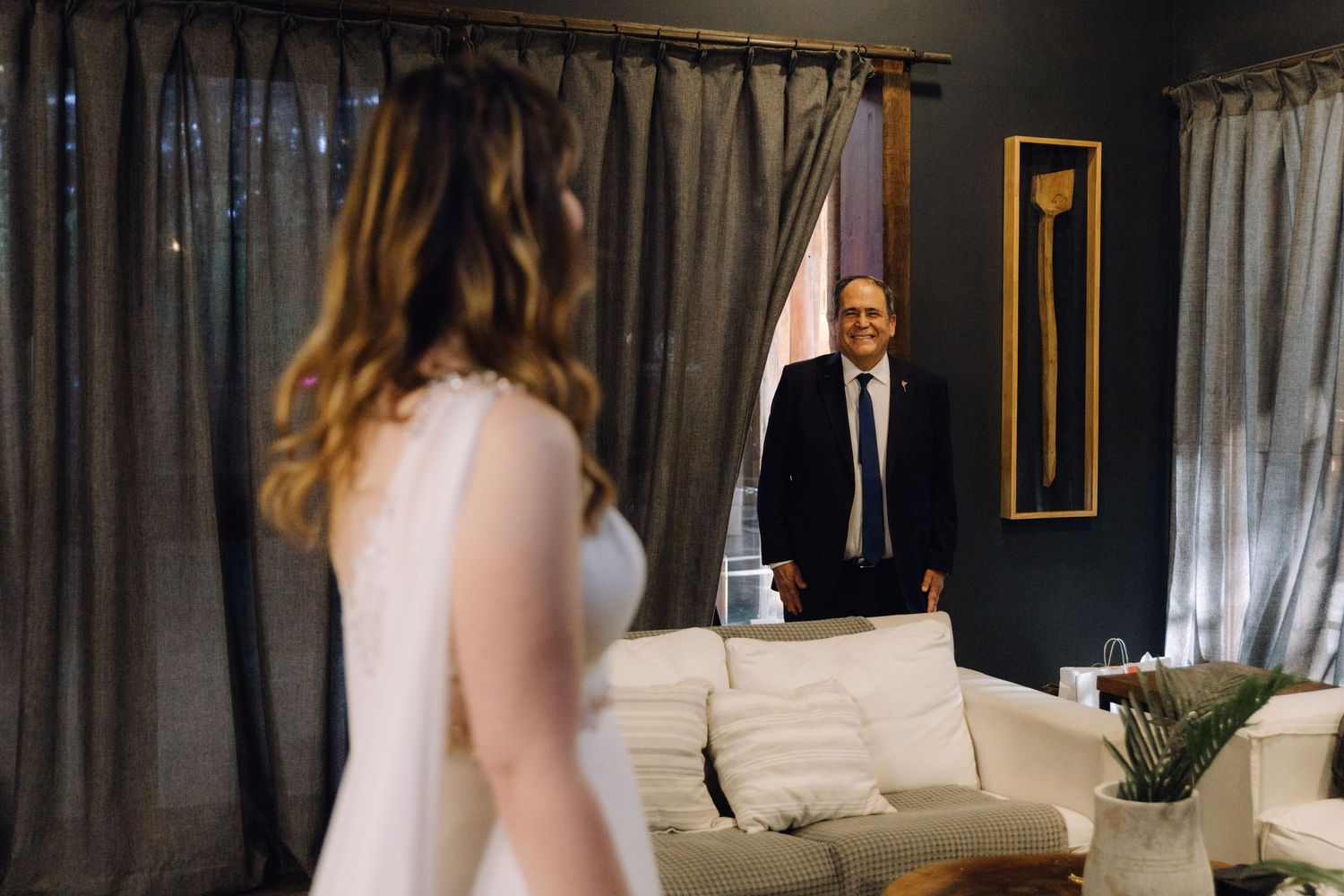 Emotional father-daughter first look moment with bride in elegant white wedding dress.