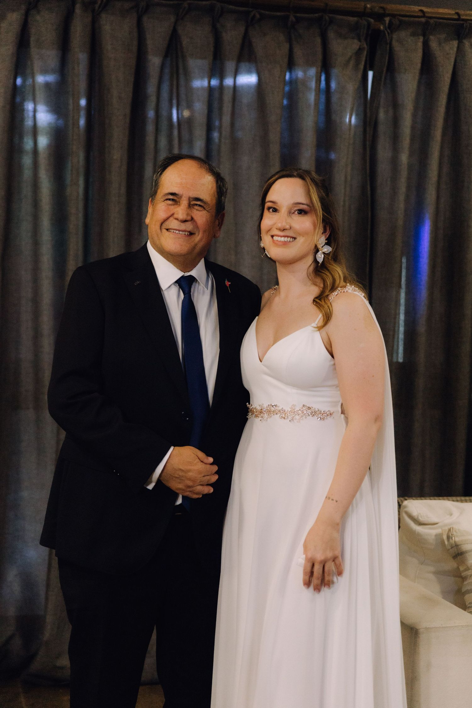 Smiling bride and proud father pose together for portrait before wedding ceremony.