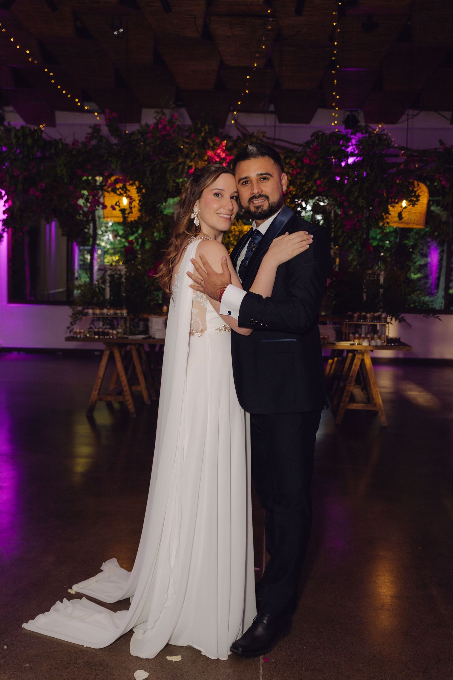 Bride and groom pose together on the dance floor at an elegant indoor wedding reception.