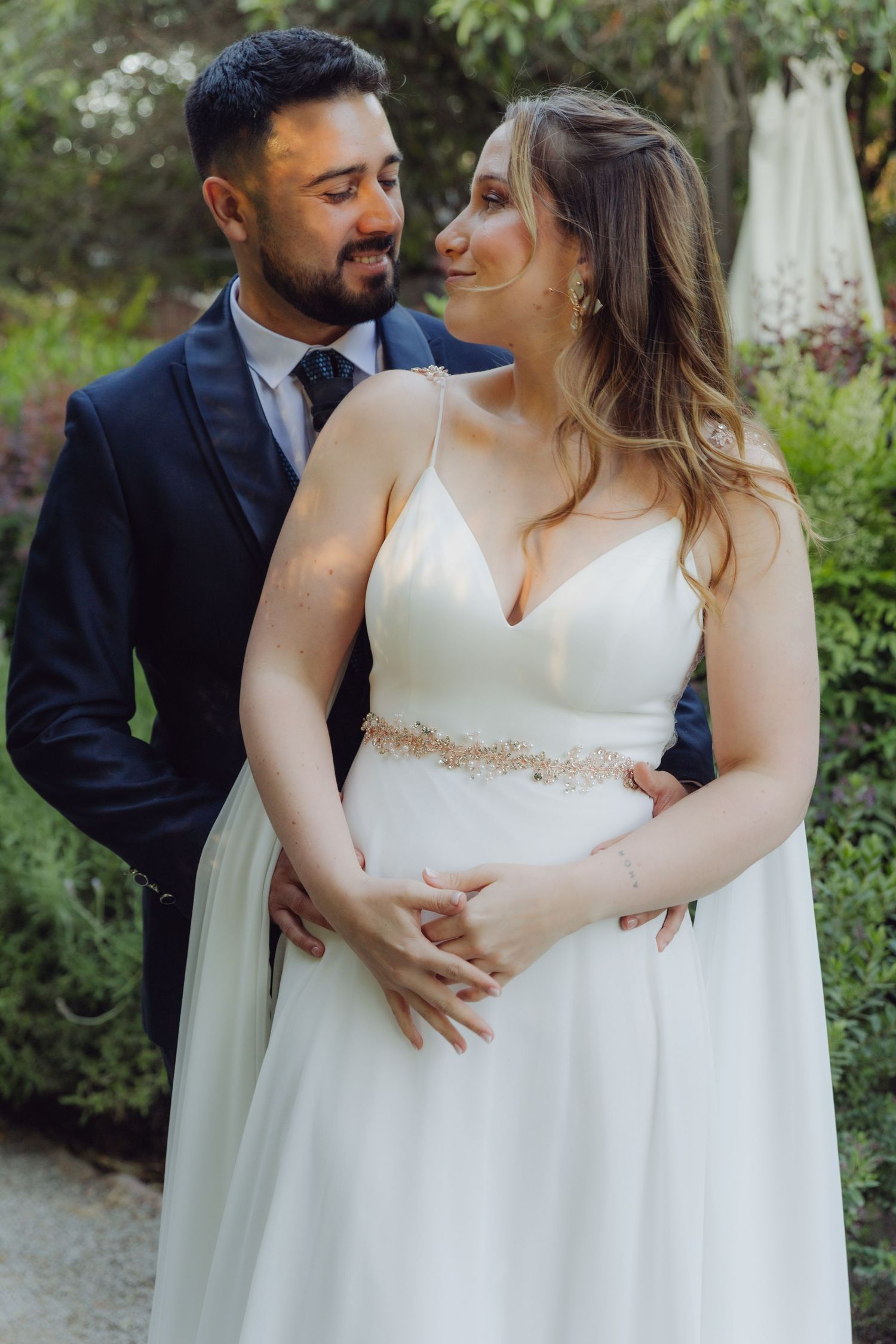 Bride and groom share a tender moment embracing in a beautiful garden setting.