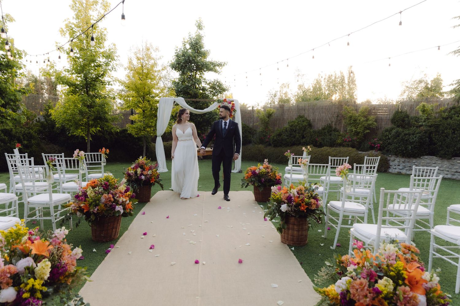 Newlyweds walk down the aisle together at an outdoor garden wedding ceremony.