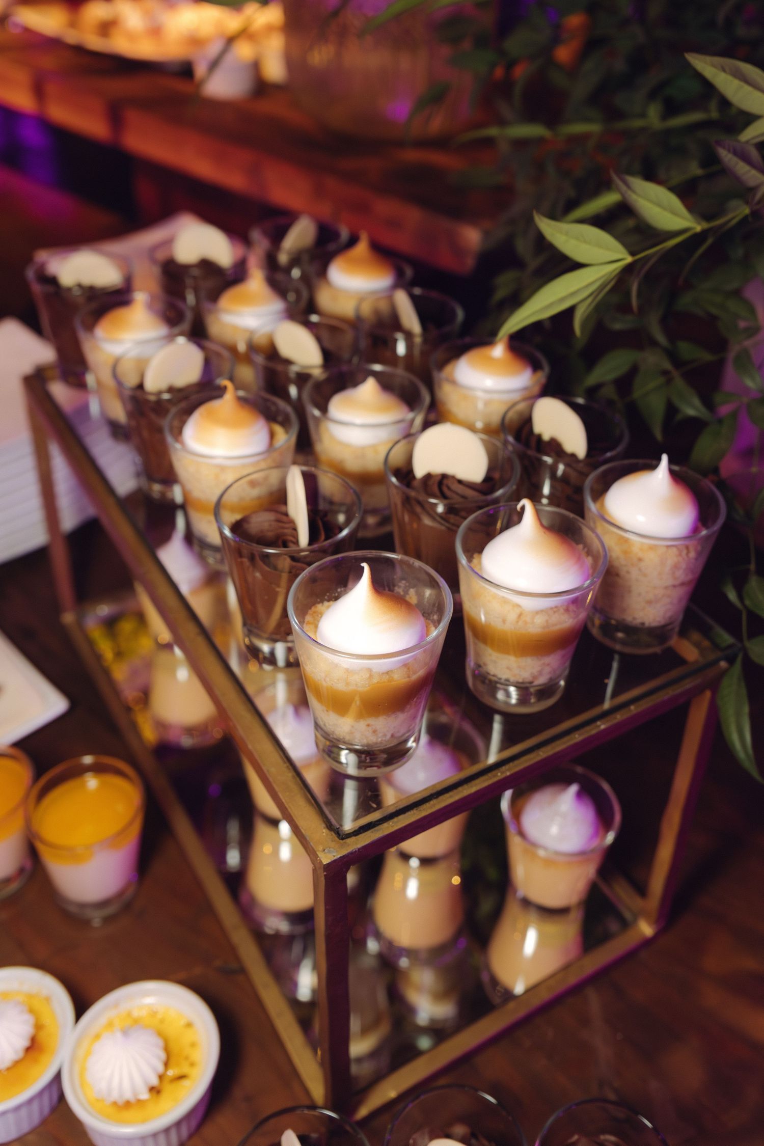 Elegant wedding dessert display featuring layered caramel mousse cups with meringue topping on gold tiered stand.
