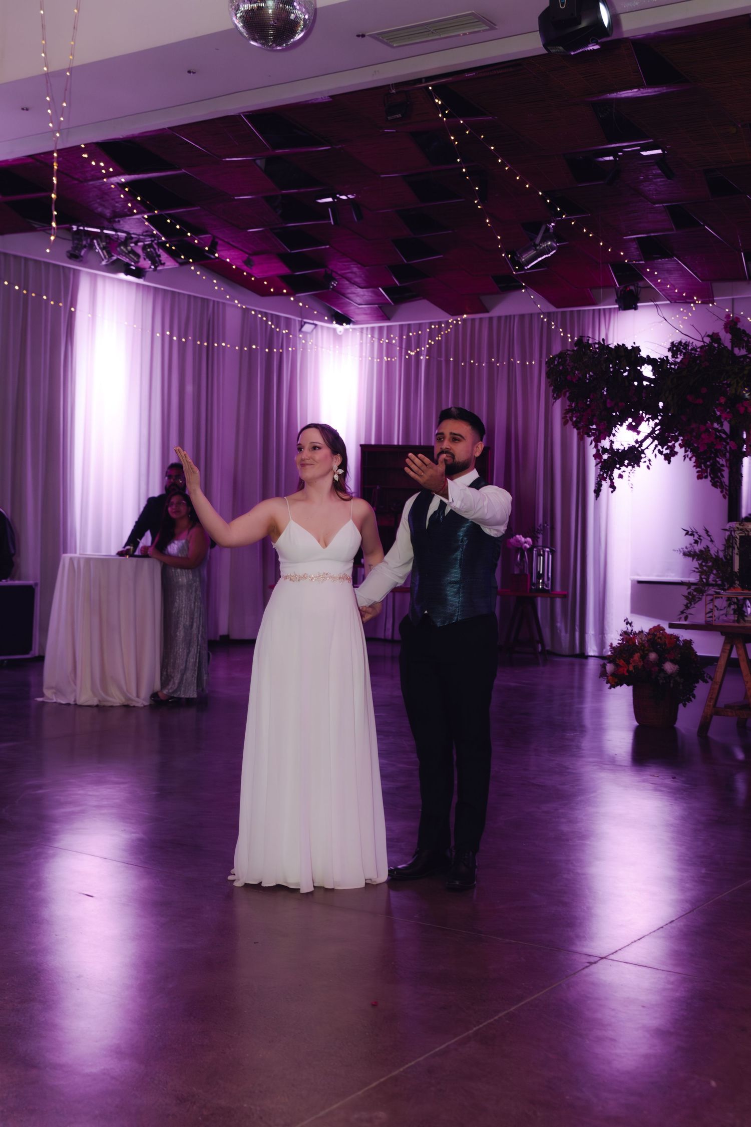 Bride and groom dance together as groom spins bride in a stunning purple-lit wedding reception ballroom.