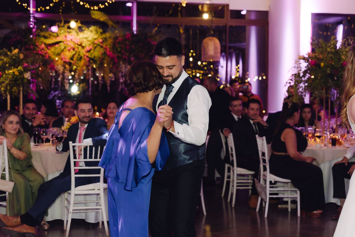 Groom sharing a tender mother-son dance at a beautifully decorated wedding reception.