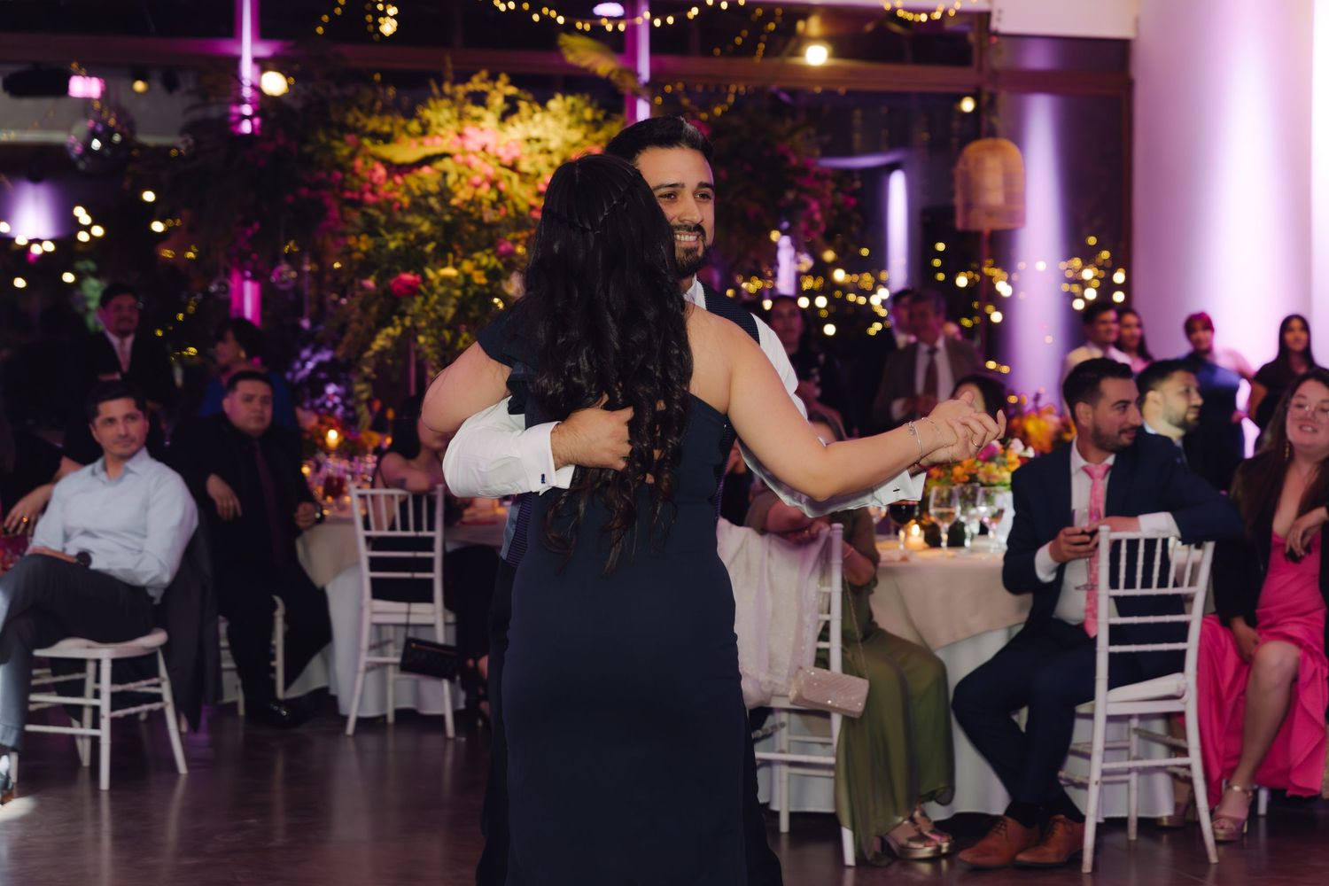 Couple sharing a joyful dance embrace at a warmly lit wedding reception.