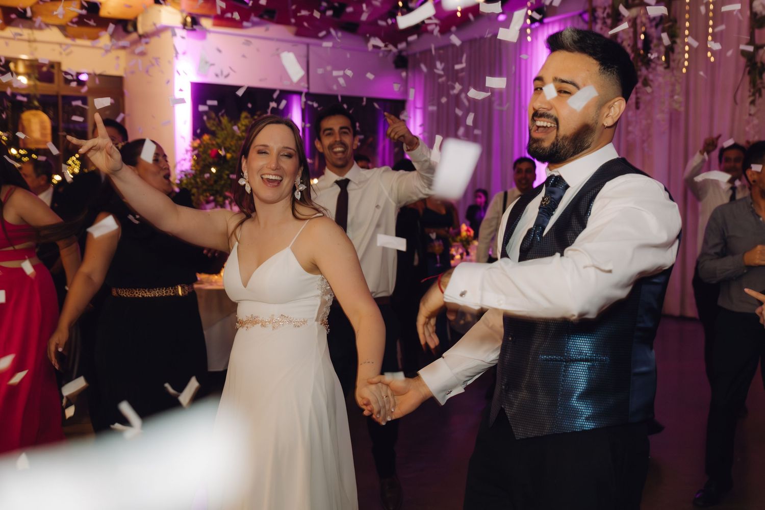 Bride and groom celebrating on the dance floor with confetti at their wedding reception.