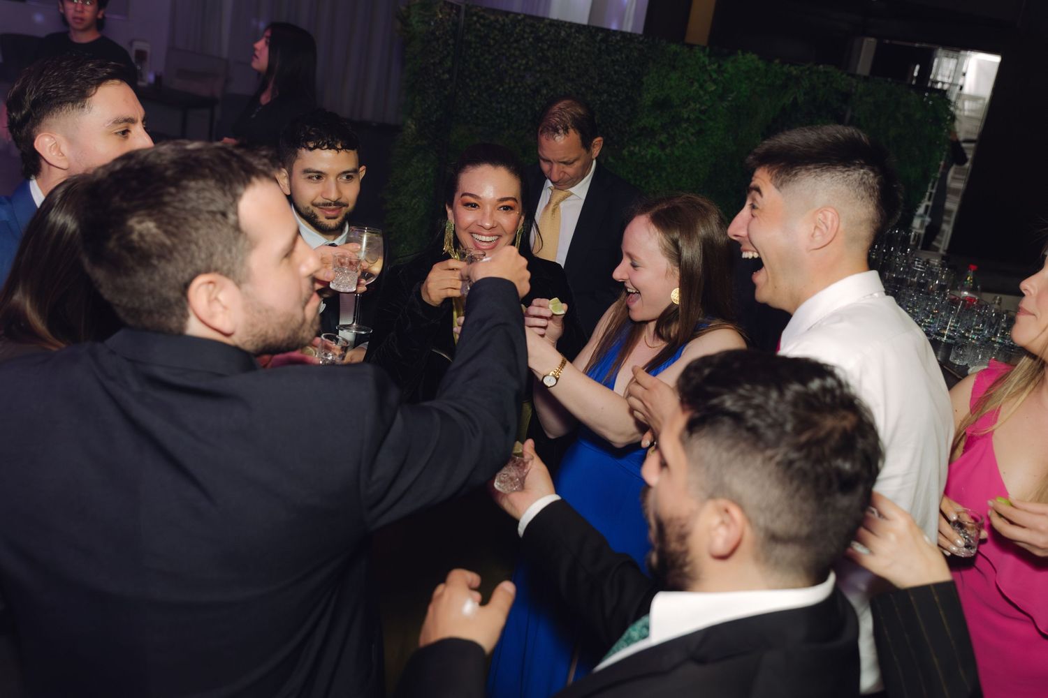 Wedding guests raise glasses in a joyful toast at the evening reception celebration.