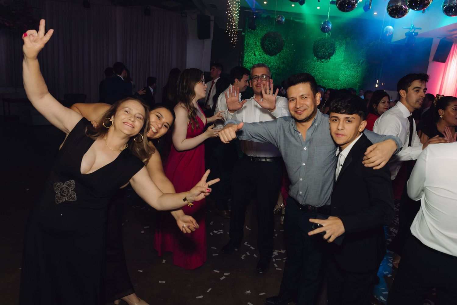 Happy group of wedding guests posing and dancing together at the evening reception.