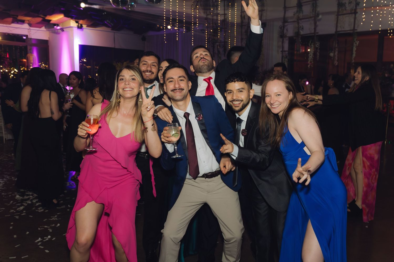 Elegantly dressed group celebrating at a festive wedding reception dance floor.