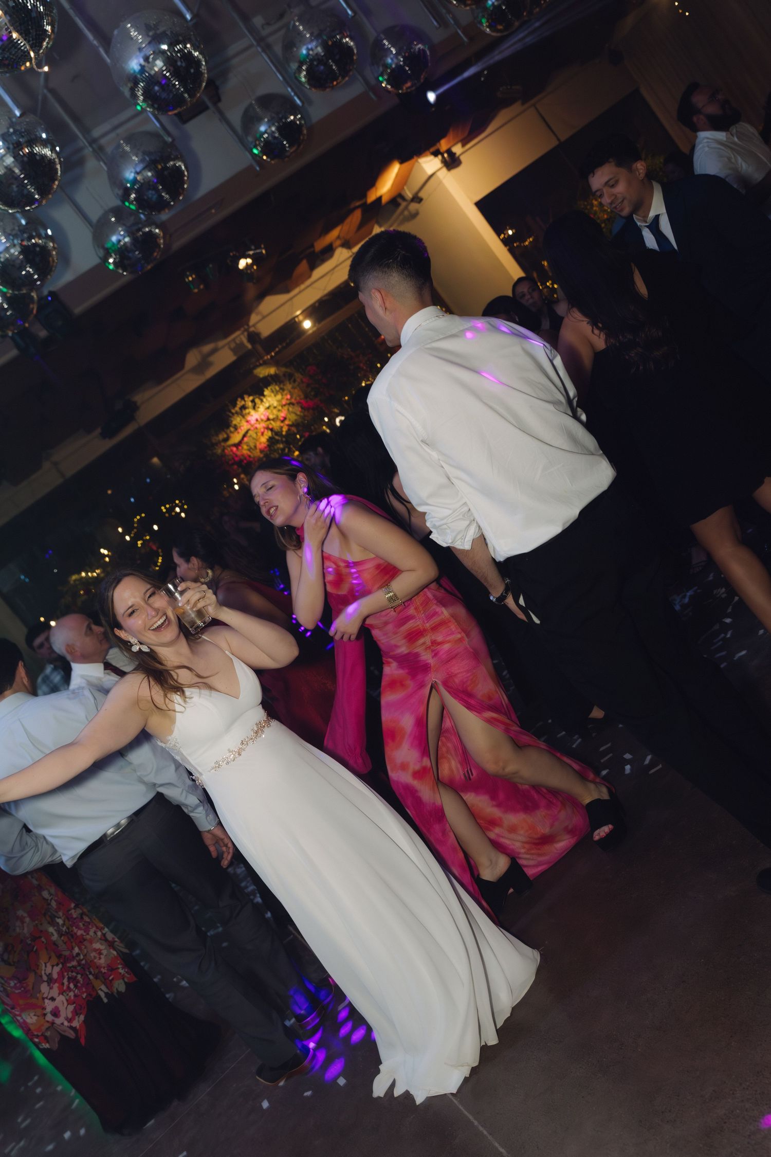 Bride in white gown dancing with guests at an elegant wedding reception.