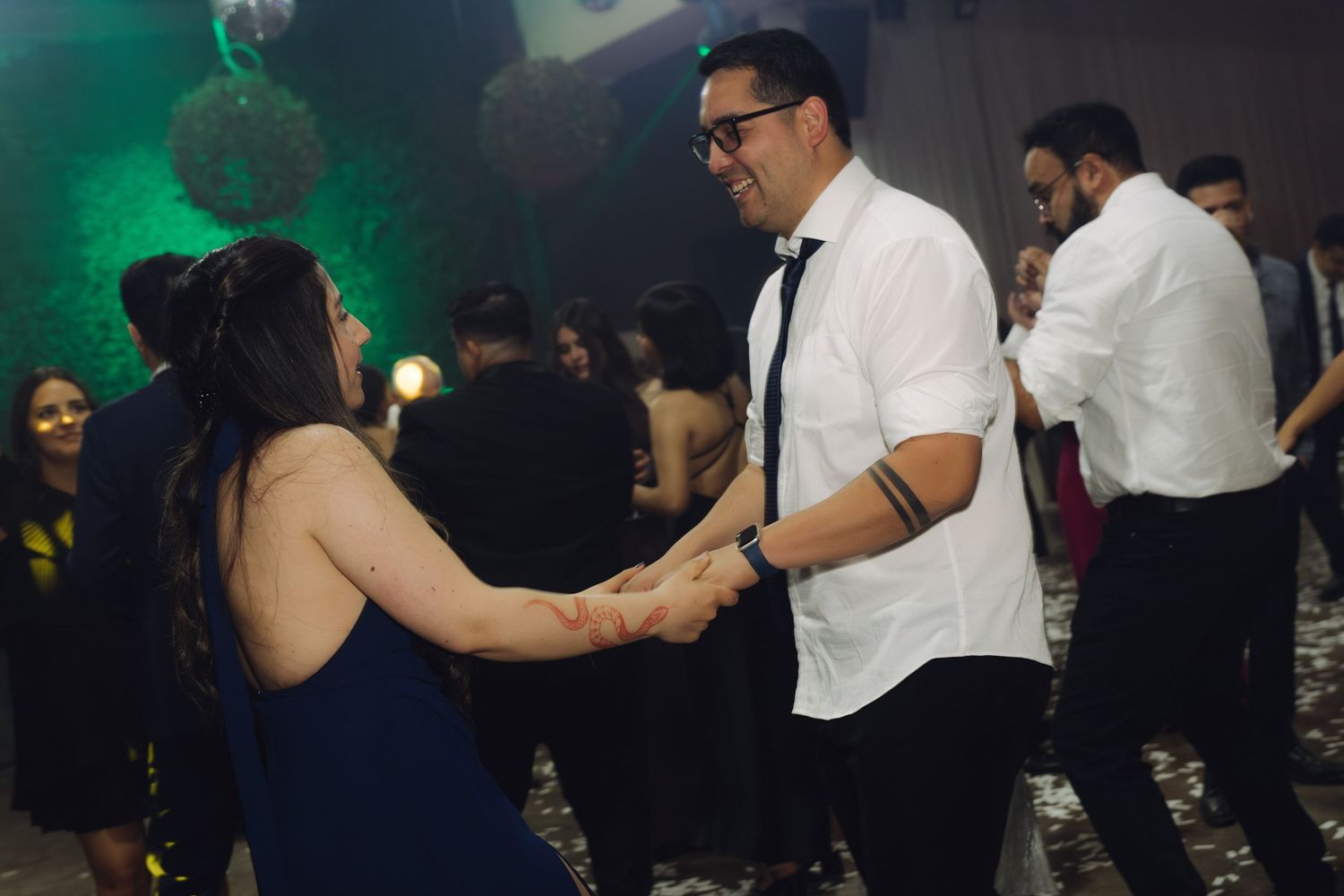 Couple holding hands and dancing together at a festive formal celebration.