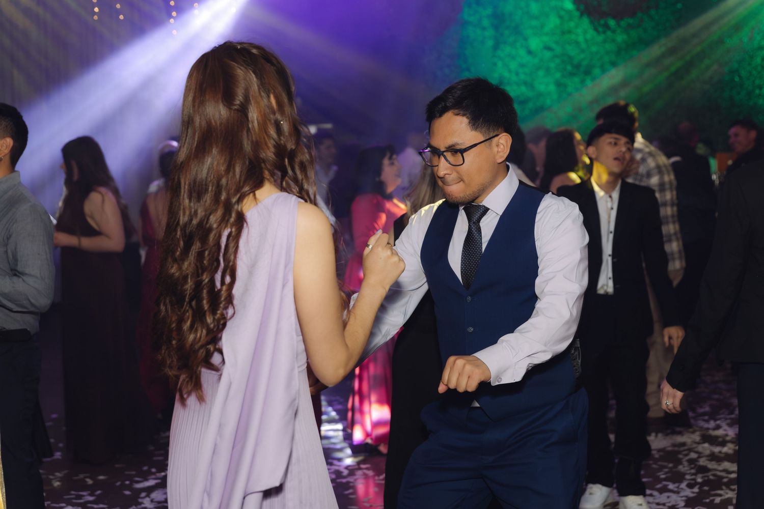 Couple dancing under stage lights at a vibrant wedding reception party.