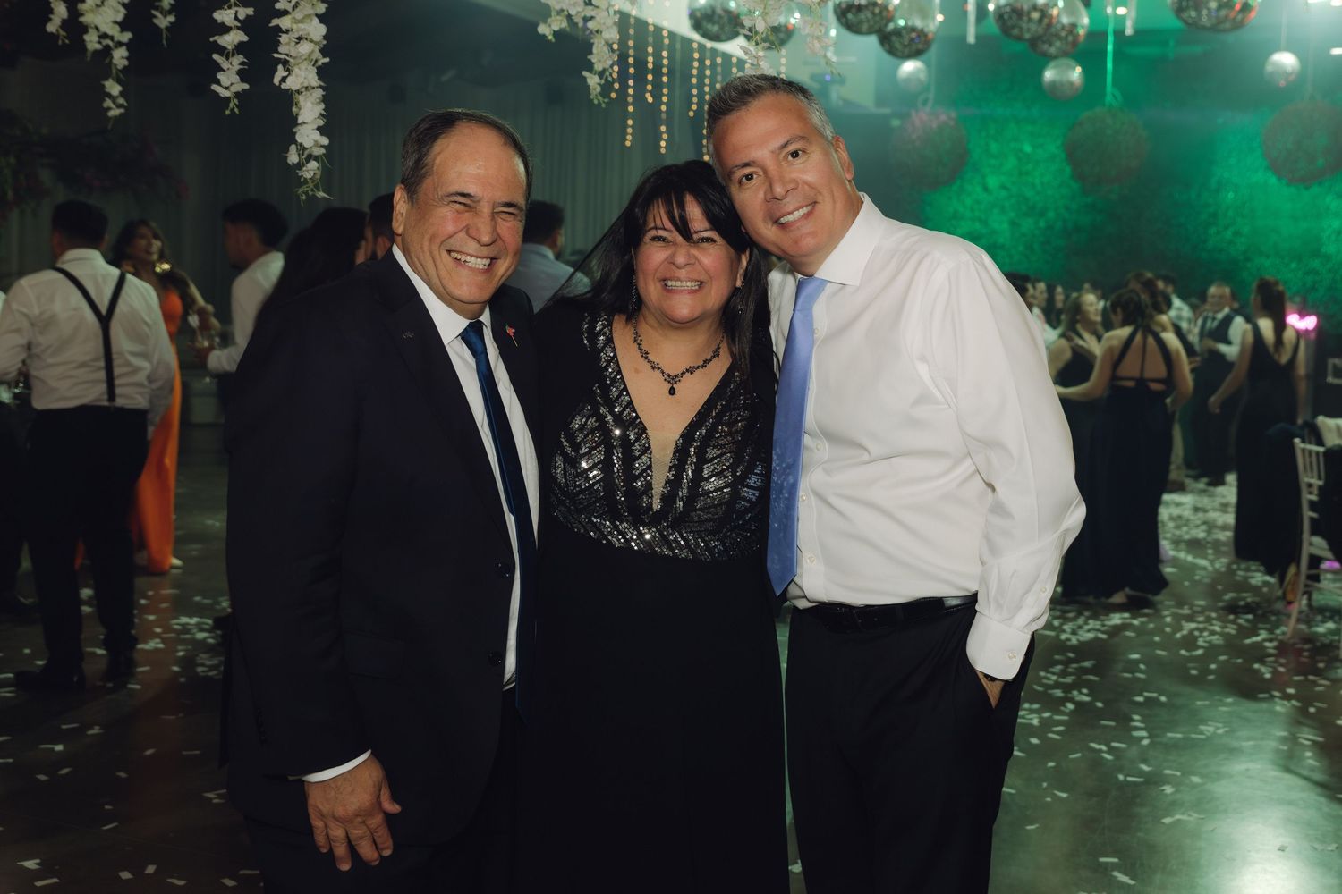 Three guests posing together and smiling at an elegant wedding reception.