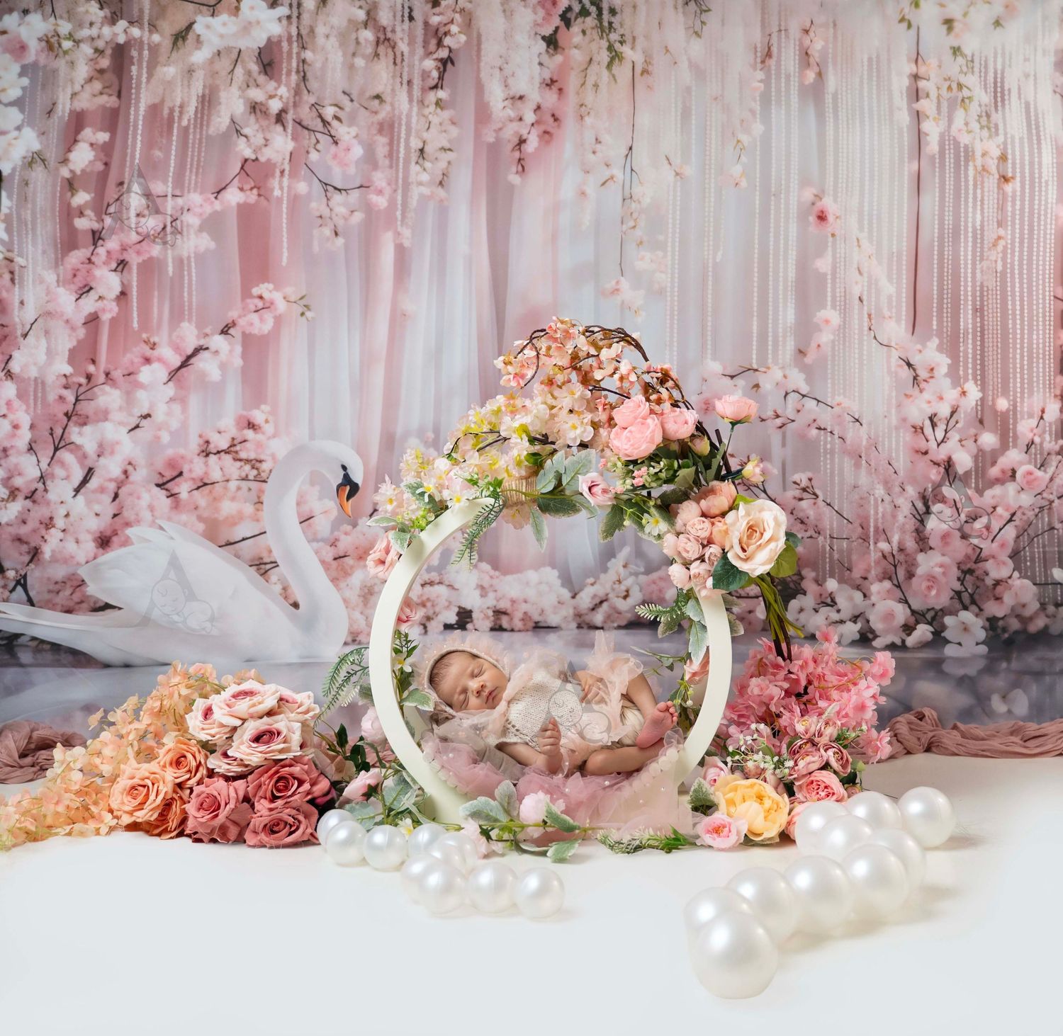 Newborn baby sleeping in a floral ring surrounded by roses and pearls with a dreamy pink backdrop.At The Affinity Studio in St. Augustine