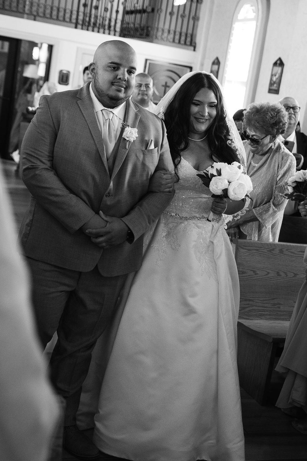 Black and white photo of a bride and groom walking down the church aisle during their wedding ceremony.